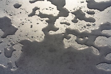 Smooth stone surface on which water lies and reflects the light.