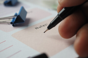 man hand writing on notepad while sited 