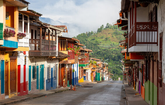 Street in Jardin, Jard&iacute;n, Antioquia, Colombia. Green background, colorful colonial facades and houses. Clouds, blue sky.