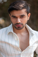 Fototapeta premium Close-up portrait of a confident, handsome Asian Indian man with his face directed towards the camera, showcasing his rich facial expressions, exuding a calm and peaceful demeanor.