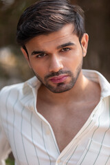 Fototapeta premium Close-up portrait of a confident, handsome Asian Indian man with his face directed towards the camera, showcasing his rich facial expressions, exuding a calm and peaceful demeanor.