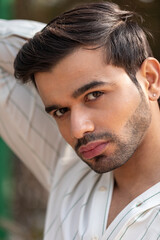 Fototapeta premium Close-up portrait of a confident, handsome Asian Indian man with his face directed towards the camera, showcasing his rich facial expressions, exuding a calm and peaceful demeanor.