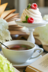 Tea in a beautiful white cup, cake with berries and white hydrangea flowers.
