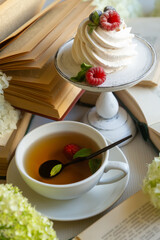 Tea in a beautiful white cup, cake with berries and white hydrangea flowers.