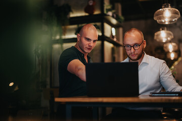 Two businessmen discussing strategy and analysis during a collaborative meeting indoors, focusing on teamwork and growth.