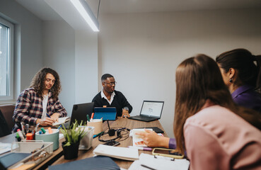 Obraz premium Diverse business professionals brainstorm in a well-lit office setting, engaging in creative teamwork and strategy development.