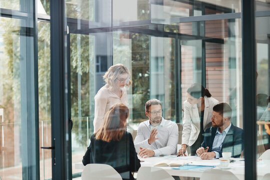 Window, business people or planning in meeting for paperwork, teamwork or collaboration together. Shareholders, investor or executive director speaking in discussion for feedback, review or project