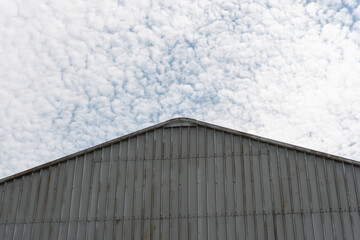 Fototapeta premium fluffy scattered clouds and shed with corrugated metal siding