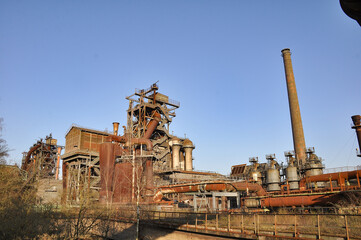 A photograph of a metallurgical plant in Duisburg showcases large-scale industrial facilities typical for the region, including a prominent blast furnace and associated metal production structures.