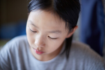 夏の家のリビングで夢中で勉強する小学生の女の子の様子