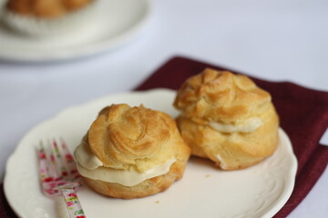 Two kue sus or profiteroles, or cream puff or choux on white plate. Selective focus