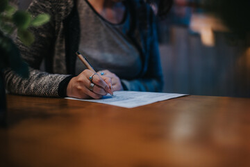 Close-up of a woman writing on a document in a dimly lit business environment at night, focused on...