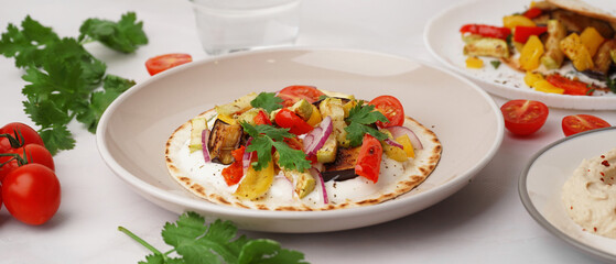 Plate of tasty pita bread with grilled vegetables on white background