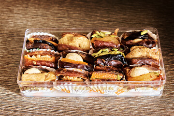 Twelve stuffed dates in a box on a dark background. Dates with nuts, a sweet dessert.