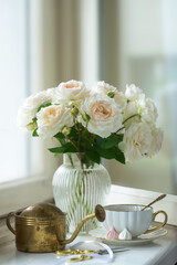 A cup of aromatic tea, a book and a rose on the table. May June July August.