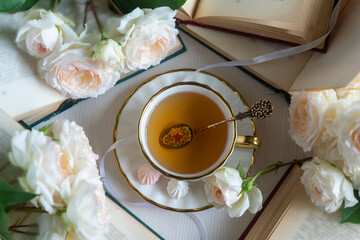 A cup of aromatic tea, a book and a rose on the table. May June July August.
