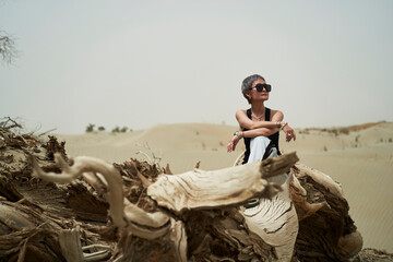 female Asian hiker sitting on dead tree trunk in desert  