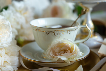 A cup of aromatic tea, a book and a rose on the table. May June July August.