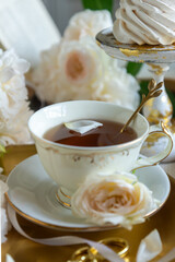 A cup of aromatic tea, a book and a rose on the table. May June July August.
