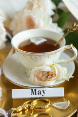 A cup of aromatic tea, a book and a rose on the table. May June July August.