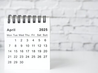 April 2025 white monthly desk calendar on a table