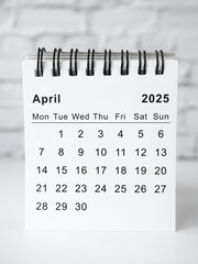 April 2025 white monthly desk calendar on a table