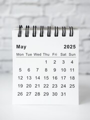 May 2025 white monthly desk calendar on a table
