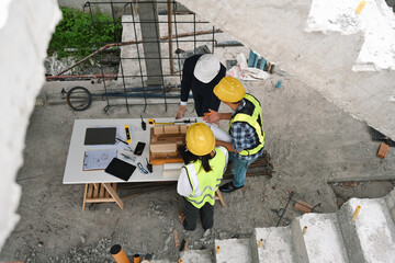 Aerial view of a two construction site meeting with a business owner, discussing plans over a table with blueprints and a building model, project planning, and strategic oversight in construction