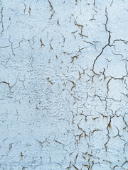 Old cracked wall with peeling blue paint showing concrete background texture