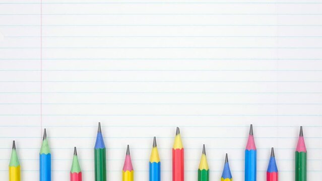 Colorful pencil bottom border with up down motion. Top view over a lined paper background. Back to school concept.
