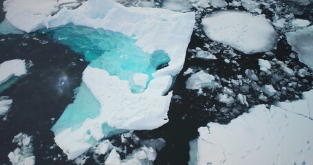 Arctic ice floes drifting cold polar ocean. Antarcica iceberg blue crystal water top view. Serene beauty of glacier surrounded by pristine icy landscapes. Global warming climate change. Aerial flight