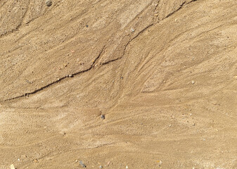 Sand on the beach as an abstract background. Sand deposits after water flow. Texture. Pattern. Selective focus