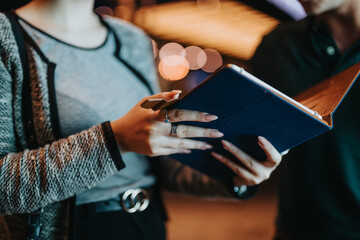 Close-up view of two people engaged in a collaborative business meeting at night, using a digital tablet for discussion.
