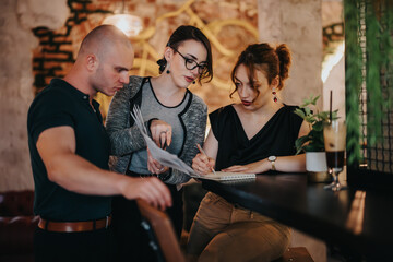 Three young entrepreneurs working together on a business project indoors, collaborating and analyzing strategies for growth and success.