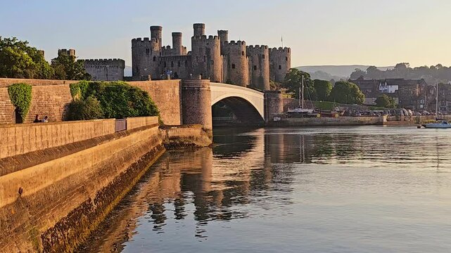 Conwy Castle at sunset with rippling reflections in the River Conwy, Wales, UK