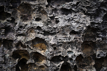 Dark grey stone wall background. Old rock with Eroded surface. Abstract pattern. Natural backdrop. Natural rock texture. Element, material design.