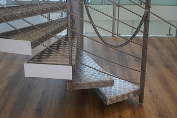 Close up of new modern spiral staircase indoors, stainless steel metal material. Wooden striped...
