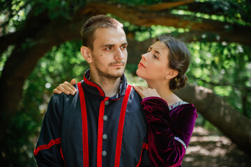 Man and woman in 19th century costumes in the forest. Woman hugs man, close-up