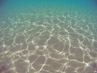 Underwater sand seabed with caustic light. Sea water background.