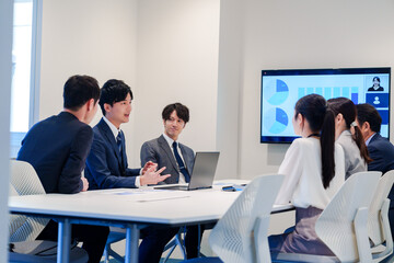 スーツを着て会議で話す若い男性