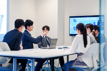 スーツを着て会議で話す若い男性