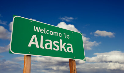 Welcome To Alaska Green Road Sign Over Blue Sky with Some Clouds. © Andy Dean