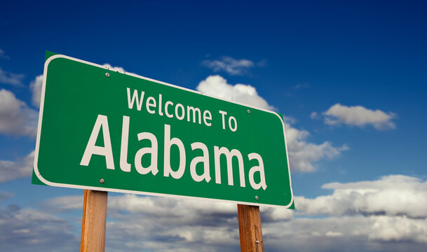 Welcome To Alabama Green Road Sign Over Blue Sky with Some Clouds.