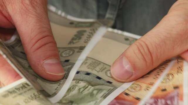 India money. The man counts Indian currency. 200 and 500 rupee banknotes