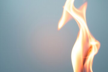 Close-up of a vibrant flame against a light blue background, highlighting the motion and intensity of fire.