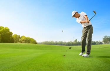 Golfer hitting golf ball with iron club.