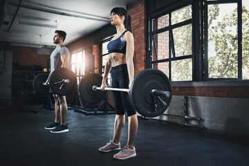 Team, fitness and workout with barbell in gym for deadlift, muscle and wellness of healthy body. Exercise, man and strong woman weightlifting for power, bodybuilding and training together at club