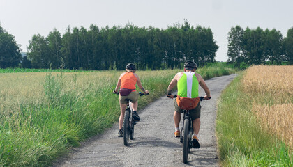 Fototapeta premium Rear View of Cyclists Riding Electric Bikes on Gravel Road