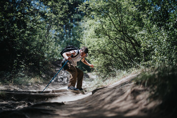 A man is hiking up a forest trail on a sunny summer day, enjoying nature, exercise, and a sense of...