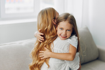 Young daughter embracing her mother on a cozy living room couch, capturing a heartwarming family moment